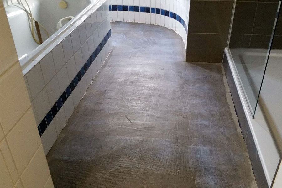 Vorbereitung des Badezimmerbodens durch Überspachteln der alten Fliesen.