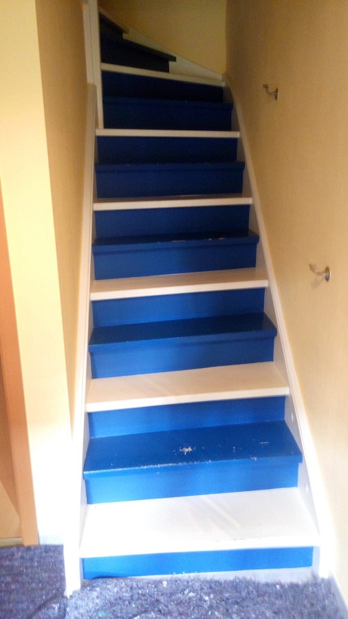 Deckend lackierte Holztreppe abgeschliffen, Trittstufen farblos lackiert sowie Setzstufen und Wangen weiß lackiert