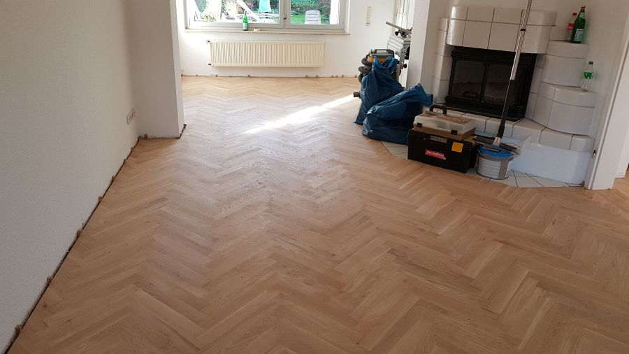 Eiche massiv Parkett, 22mm stark, im Fischgrat Verband verlegt und endbehandelt. Inkl. Fußleistenmontage.