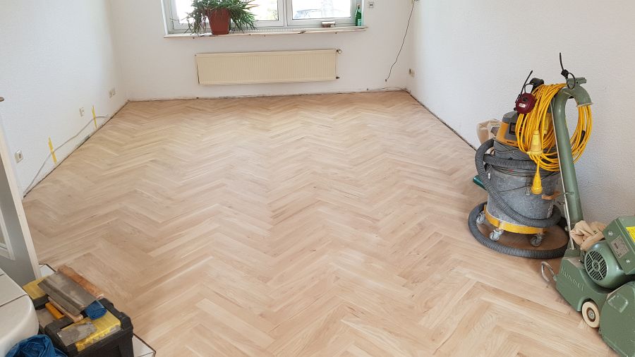 Eiche massiv Parkett, 22mm stark, im Fischgrat Verband verlegt und endbehandelt. Inkl. Fußleistenmontage.