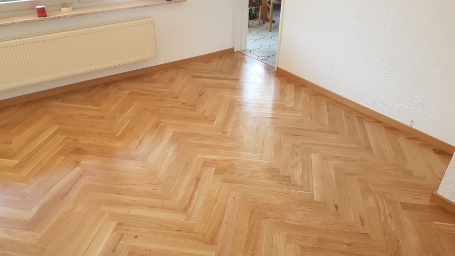 Eiche massiv Parkett, 22mm stark, im Fischgrat Verband verlegt und endbehandelt. Inkl. Fußleistenmontage.