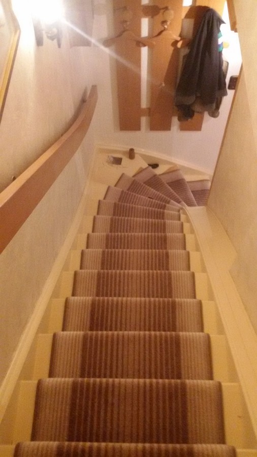 Treppenläufer auf einer Holztreppe verlegt und die gewendelten Stufen fachmännisch eingenäht