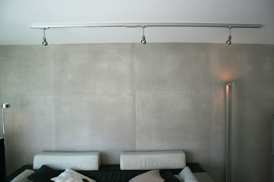 Großflächige Wandgestaltung in Betonoptik hinter einer Couchgarnitur.